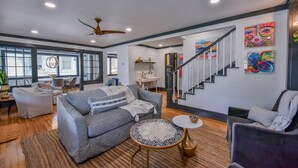 A spacious living room with a grey sofa, a round coffee table, and a staircase leading to another level.