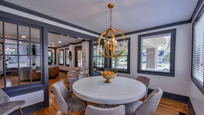 A modern dining area with a round table, six chairs, and a chandelier.