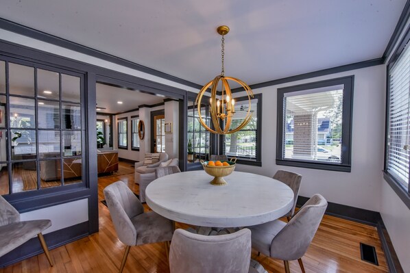 A modern dining area with a round table, six chairs, and a chandelier.