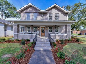A two-story house with a front porch, a covered entryway, and a driveway leading to the front door.