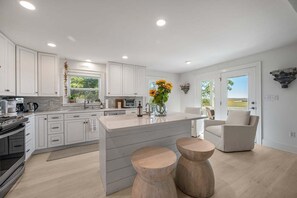 A modern kitchen with white cabinets, a central island, and a view of the outdoors. - Waterfront Vacation Rental in Darien, GA | Private Hot Tub & Dock (Darien)