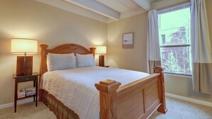 A bedroom with a wooden bed, two bedside lamps, a window with curtains, and a framed picture on the wall. - 2 Bedroom Condo Just off Frisco Main Street. B207 (Frisco)