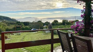 Eine Holzterrasse mit Blick auf eine Rasenfläche, einer Bank und einer Pergola.
