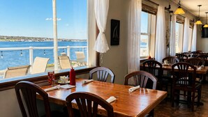 Un restaurante con vista al agua, mesas y sillas de madera.