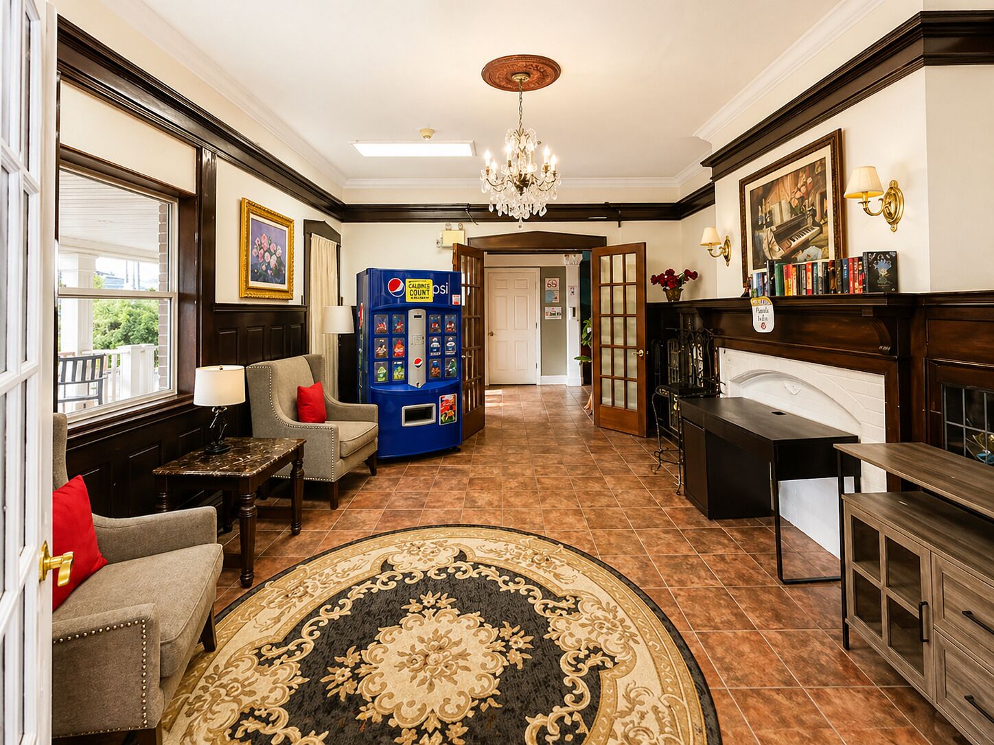 Um hall com lareira, área de estar, máquina de vendas automática e um candelabro.