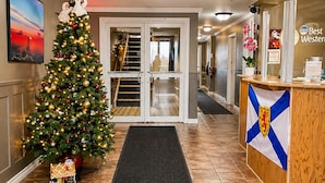 Un vestíbulo de hotel con un árbol de Navidad, una recepción y una escalera que conduce a los pisos superiores.