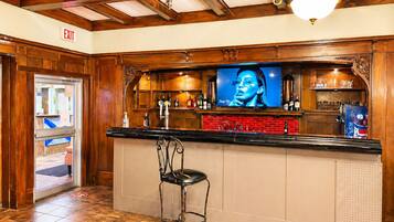 Zona de bar con televisión, taburetes y mostrador rojo.