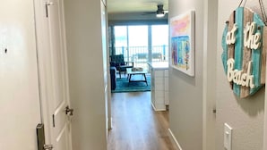 A hallway with wooden flooring leading to a dining area with a table and chairs. - RENOVATED 10/21! Corner Oceanview Condo w/ AC!! (Kapaa)