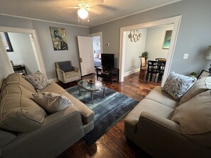 Un salon avec deux canapés, une table basse, un téléviseur et un ventilateur de plafond.