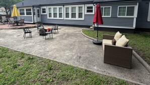 A covered patio area with outdoor furniture, including tables and chairs, and two umbrellas.