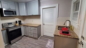 A compact kitchen with white cabinets, a microwave, a coffee maker, and a granite countertop.