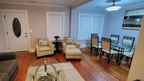 A living room with a sofa, armchairs, a coffee table, and a dining area with chairs and a table.