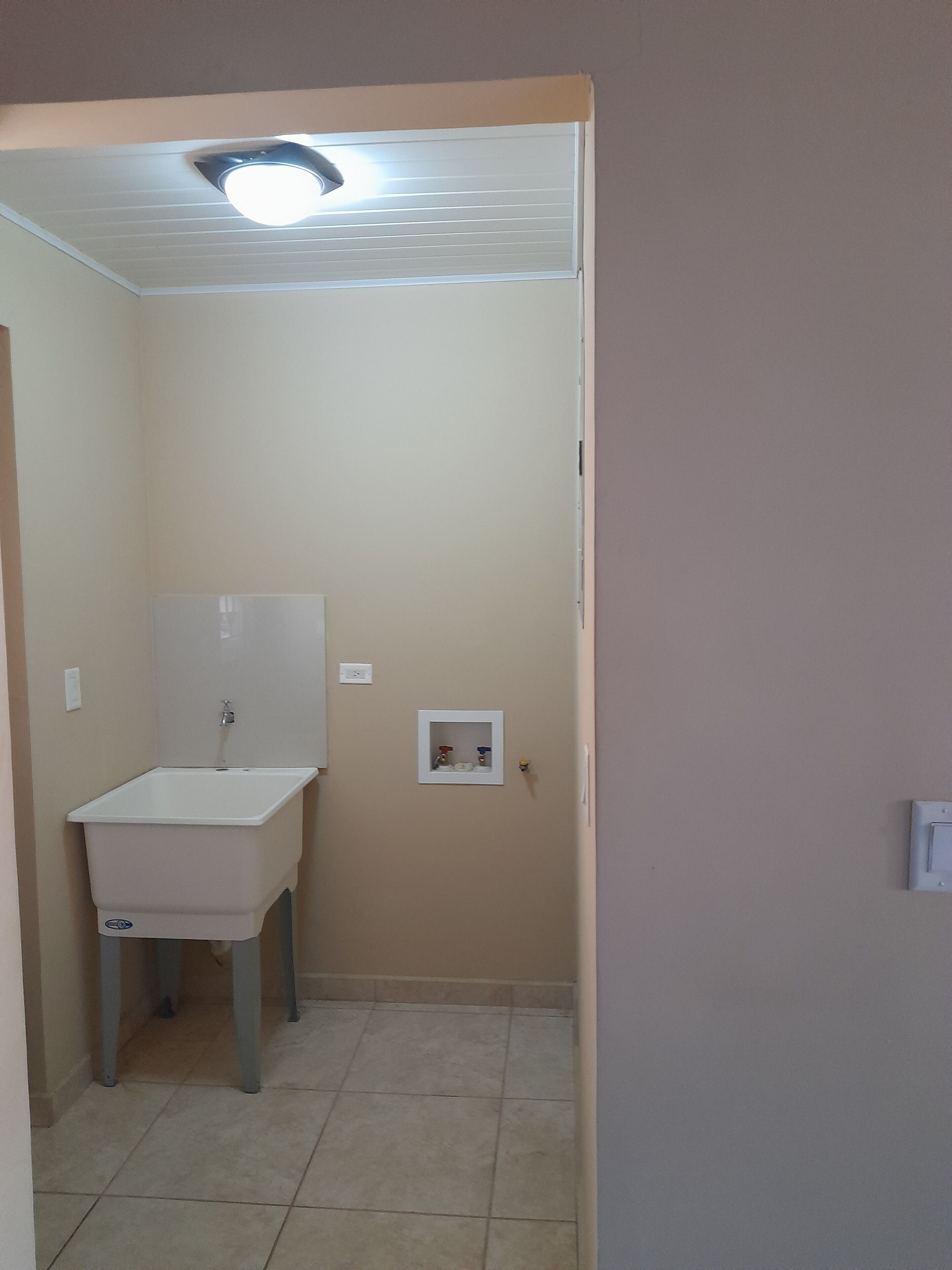 Un baño pequeño con un lavamanos blanco, un espejo y una lámpara en el techo.