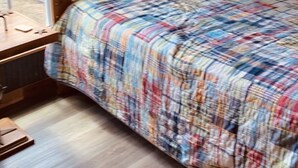 A bunk bed with a plaid bedspread, a window with a view of trees, and a wooden desk with a chair. - The Cabin at Crosswind Ranch  (Comanche)