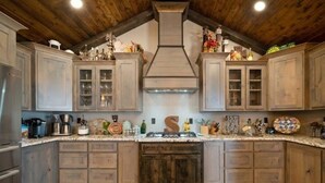 Een keuken met houten kasten, een centraal eiland en een rustiek plafond.