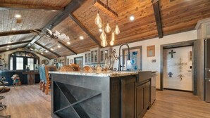 Een ruime keuken met een groot eiland, houten balken in het plafond en hanglampen.