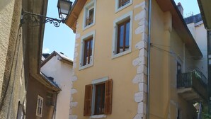 Un edificio con un cortile in pietra, una porta in legno e una scala che conduce a un piano superiore.