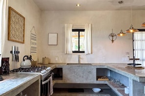 Une cuisine de taille réduite, équipée d’une cuisinière à gaz, d’un four et d’une fenêtre avec des rideaux.