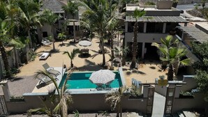 A resort with a pool, palm trees, and a mountainous backdrop.