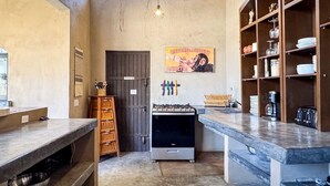 A compact kitchen with a gas stove, wooden cabinets, and a coffee machine.