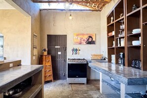 A compact kitchen with a gas stove, wooden cabinets, and a coffee machine.