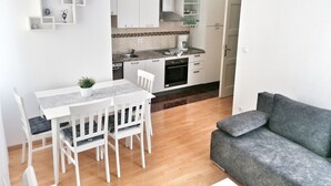 A compact kitchen with white cabinets, a dining area with a table and chairs, and a grey sofa. - Top location (150 m- Bacvice, 400 m-Diocletian’s Palace, 5-minute walk to ferry) (Split)