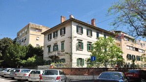 A multi-story building with a balcony on the second floor, parked cars in front, and a clear blue sky. - Top location (150 m- Bacvice, 400 m-Diocletian’s Palace, 5-minute walk to ferry) (Split)
