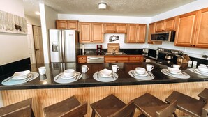 A modern kitchen with wooden cabinets, stainless steel appliances, and a central island with bar stools. - 3 min Walk to Slopes, Great Views, Shared Hot Tub  (Frisco)