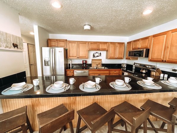 A modern kitchen with wooden cabinets, stainless steel appliances, and a central island with bar stools.