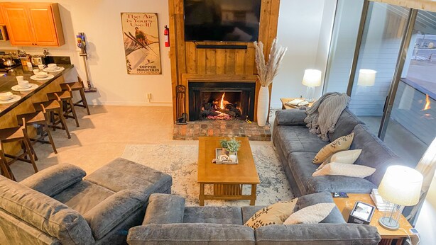 A cozy living room with a fireplace, a sofa set, a coffee table, and a dining area with chairs. - 3 min Walk to Slopes, Great Views, Shared Hot Tub  (Frisco)