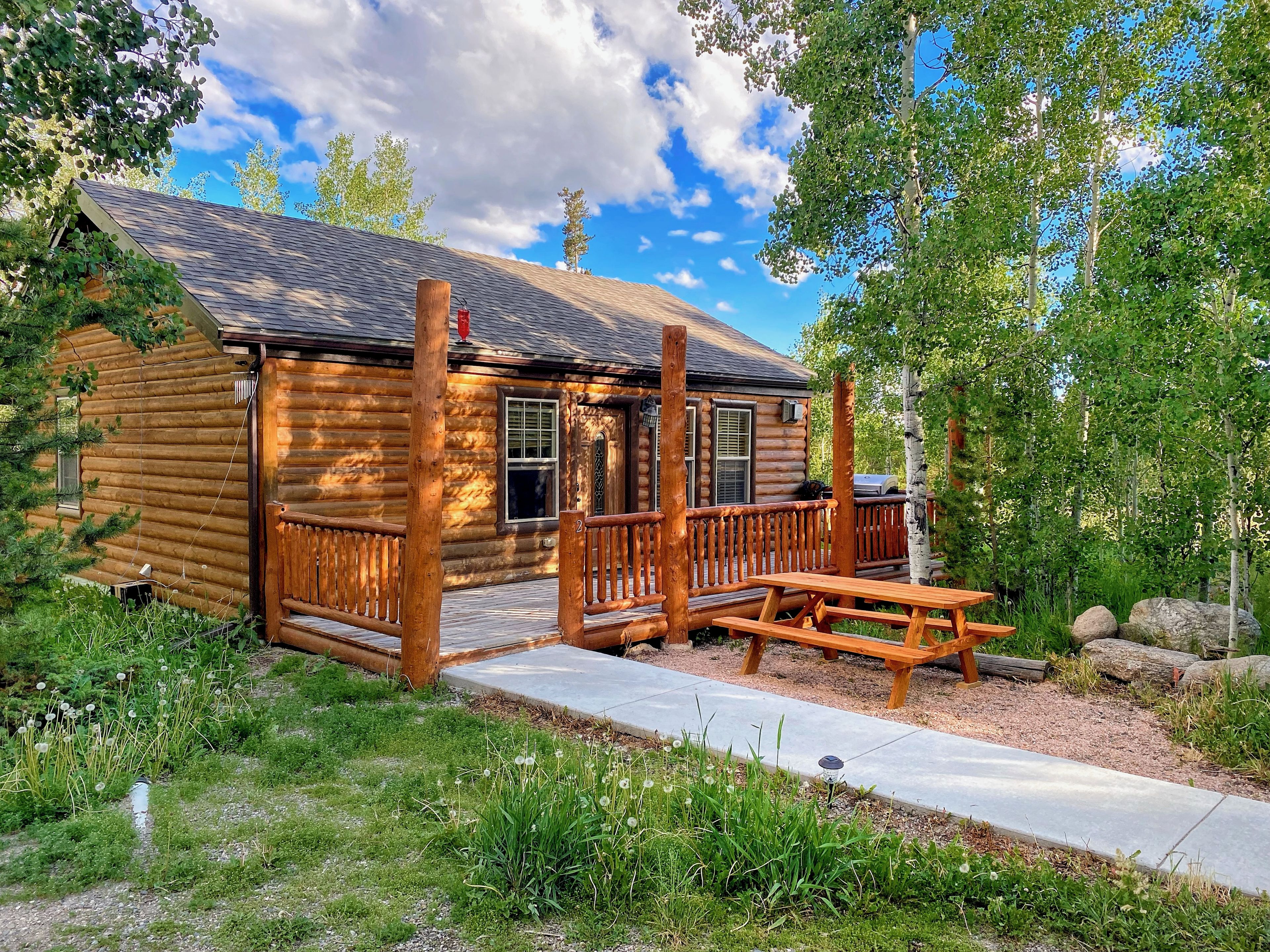 Une cabane en rondins avec une terrasse en bois et une table de pique-nique.