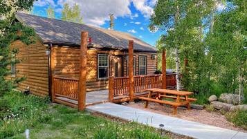 Une cabane en rondins avec une terrasse en bois et une table de pique-nique.