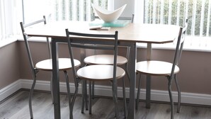 A dining area with a table and four chairs, a bowl on the table, and a window with blinds. - Modern 1-Bed Apartment – 3 Min Walk to HOST & Pitman, Leeds (Leeds)