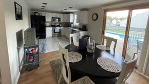 A kitchen with white cabinets, a microwave, and a stove. There is a dining table with white chairs and a black tablecloth. - 3 bedroom house with fenced in yard and pool close to Syracuse (Cicero)