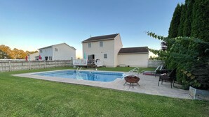 A backyard with a swimming pool, a hot tub, and a deck area with chairs. - 3 bedroom house with fenced in yard and pool close to Syracuse (Cicero)