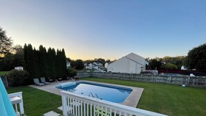 A backyard with a swimming pool, a deck with outdoor furniture, and a wooden fence. - 3 bedroom house with fenced in yard and pool close to Syracuse (Cicero)