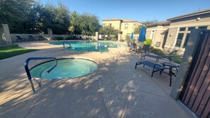 A backyard with a swimming pool, lounge chairs, and a patio area.