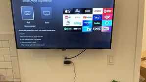 Un téléviseur à écran plat fixé au mur affiche un menu de sélection pour les services de diffusion en continu.