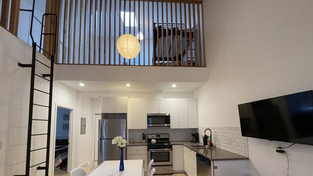 Une cuisine moderne avec un coin repas, un téléviseur fixé au mur et un balcon avec vue.