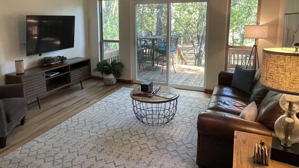 A living room with a TV, sofa, coffee table, and a view of the outdoors through large sliding doors.