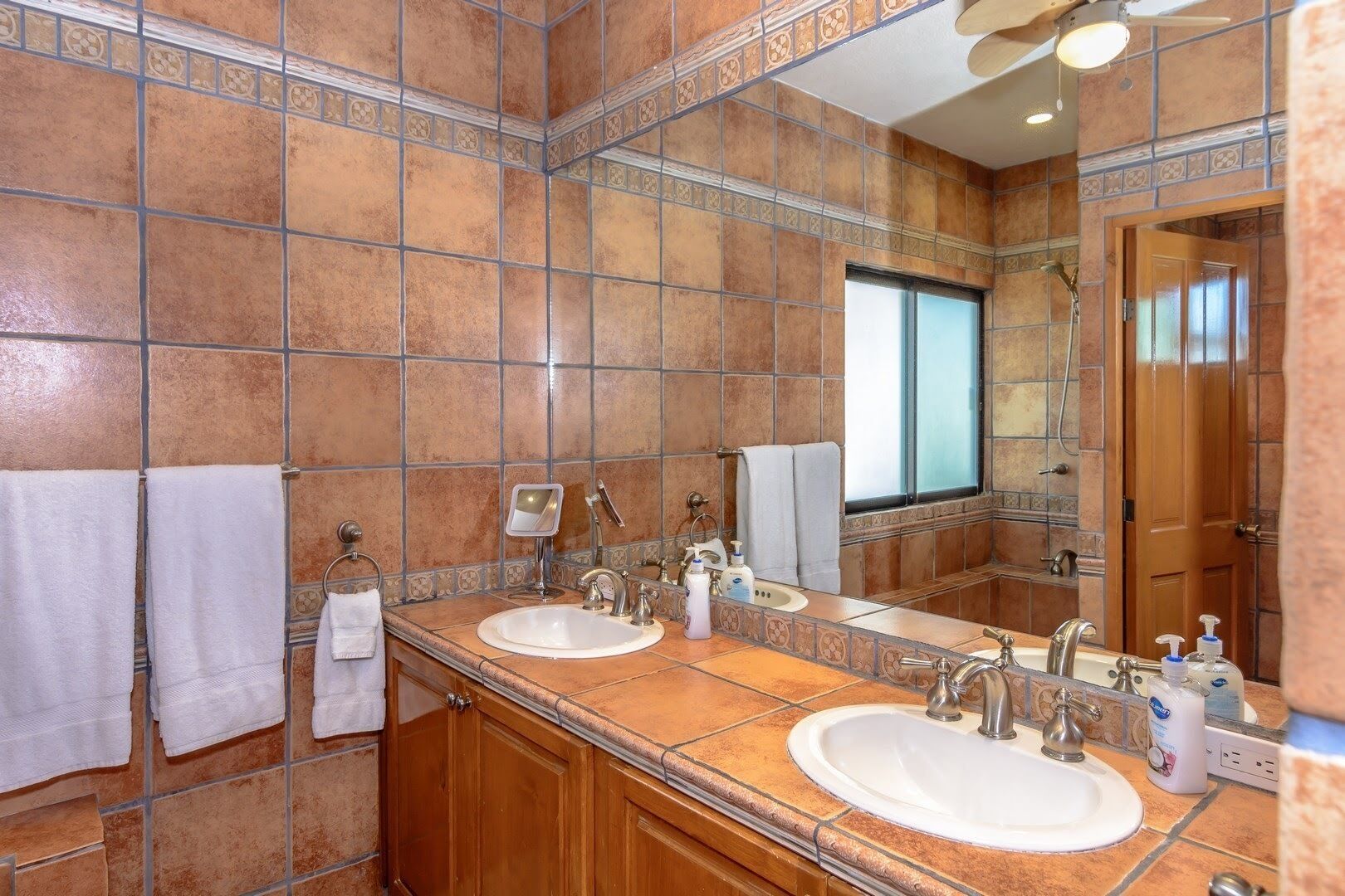Un baño con dos lavamanos, un espejo y una ventana.