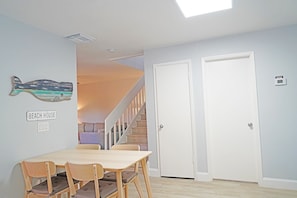A dining area with a wooden table and chairs, a wall-mounted fish decoration, and a staircase leading to another room.