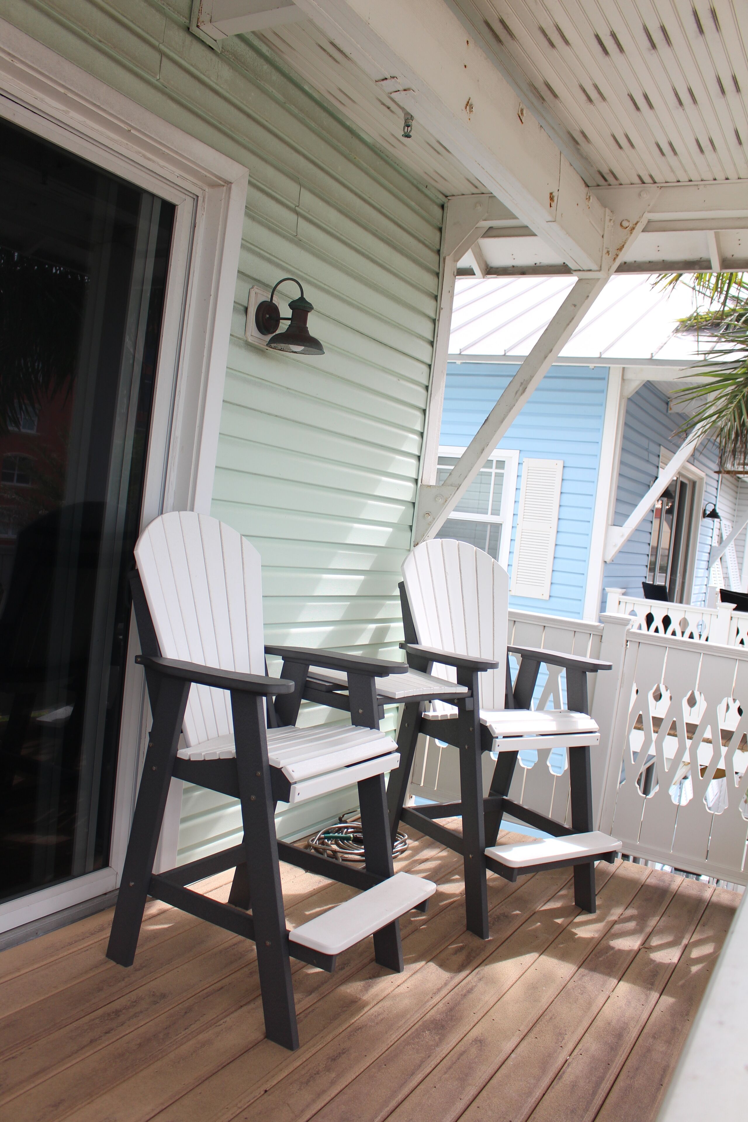 A wooden deck with two white Adirondack chairs and a small table.