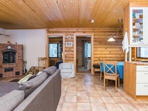A cozy log cabin interior with a fireplace, a sofa, a dining table, and a kitchen area. - Vacation home Muikku by Interhome (Punkaharju)