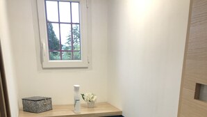 A small bathroom with a toilet, a sink with a mirror, a window, and a towel dispenser.