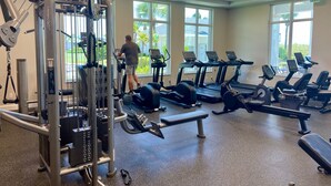 Une salle de sport équipée de tapis de course, d’appareils de musculation et d’un banc.