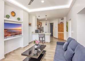 Uma sala de estar moderna com uma televisão de tela plana, um sofá e uma mesa de centro.