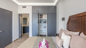 A bedroom with a bed, a wooden headboard, a wardrobe, and a built-in shelf unit. - AWESOME OCEAN VIEWS, GREAT LOCATION, PERFECT VACATION (Cabo San Lucas)