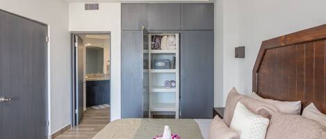 A bedroom with a bed, a wooden headboard, a wardrobe, and a built-in shelf unit.