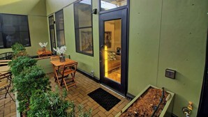 A room with a bed, a window, a door, and a small table with a vase. - Chic Ultramodern Minimalist Studio Loft + Patio (Saint Louis)